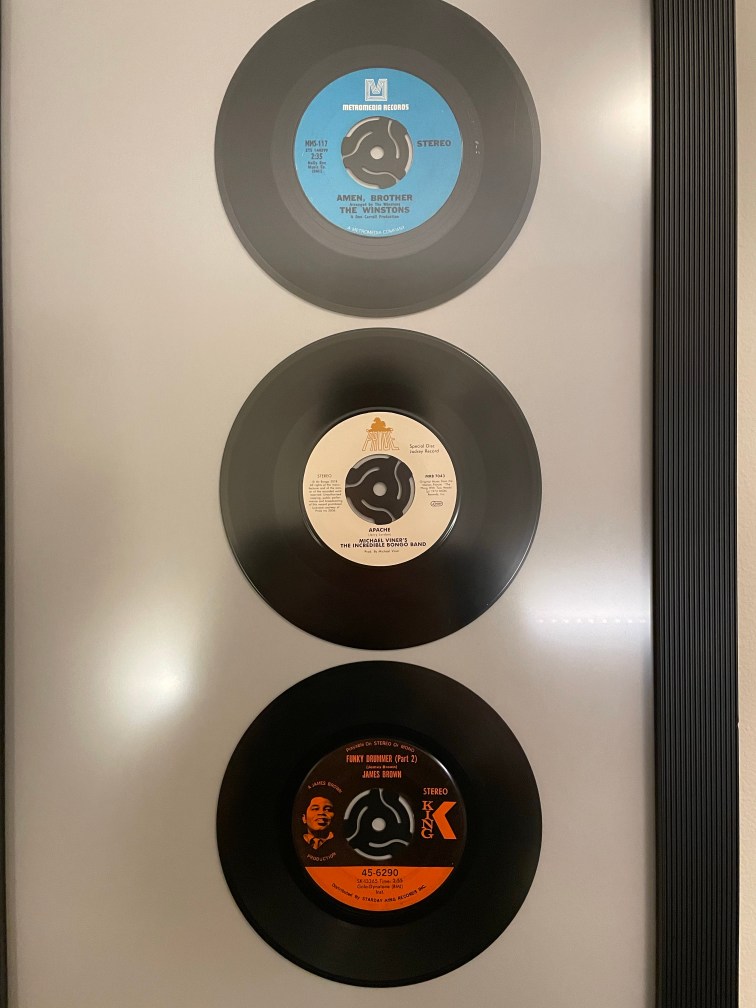 A framed display of three most-sampled 45 rmp records: Amen, Brother (The Winstons), Apache, and Funky Drummer (James Brown) on my wall.